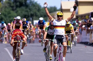 Pro male German rider André Greipel crossing the finish line on his bike after a sprint finish, he's throwing his hands in the air after winning stage 1 of the Tour Down Under in 2013